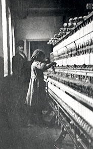 Hines photo of little girl tending dozens of spindles with overseer in background.