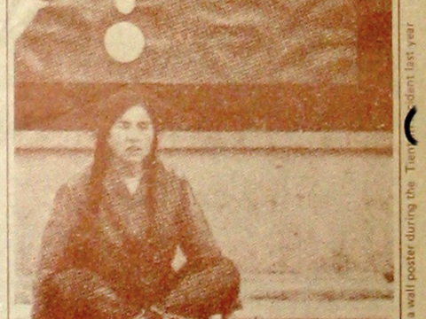 Women sitting below a wall poster during the Tienamen incident last year