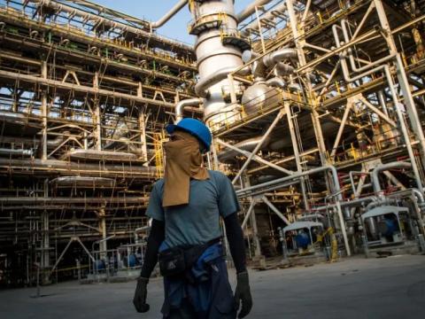 A worker with his face covered with a safety cloth walks through the Bushehr Petrochemical Co. plant during construction work in the Pars Special Economic and Energy Zone in Asaluyeh, Iran