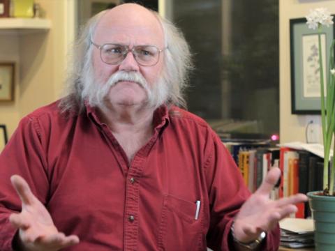 Barry Pateman in a red shirt with his hands spread out
