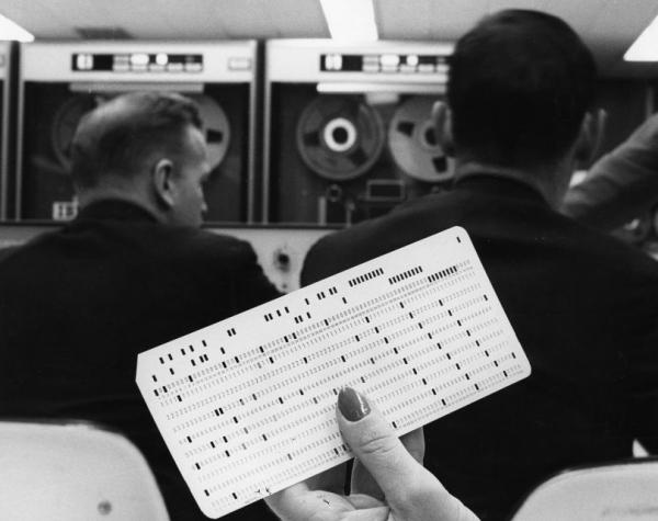 a female white hand with painted nails holds a computer punch card