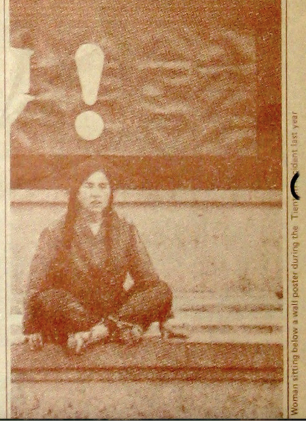 Women sitting below a wall poster during the Tienamen incident last year