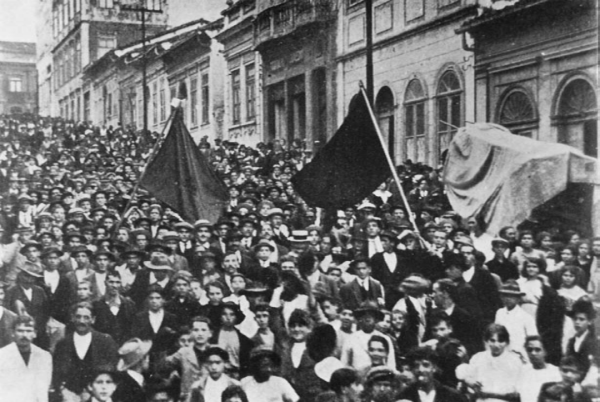 A black and white old picture of anarchists protesting with black flags