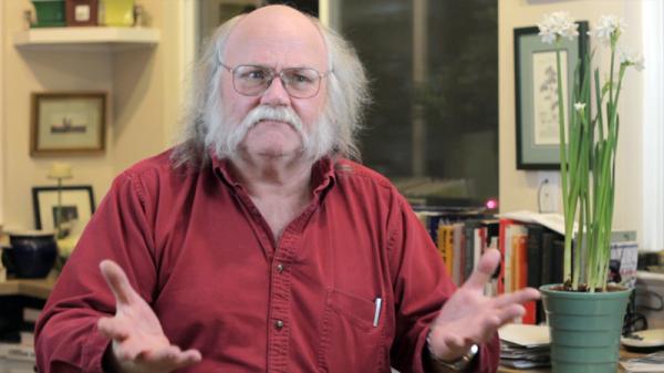Barry Pateman in a red shirt with his hands spread out