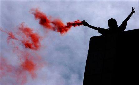 Greek firefighter lights a flare during occupation of fire service headquarters.