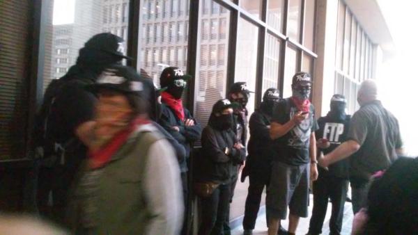 The collective addressing the media before the city council meeting, outside the chambers. All are wearing "Fuck the Police" hats. (Photo credit: Saraí J. Santamaría)